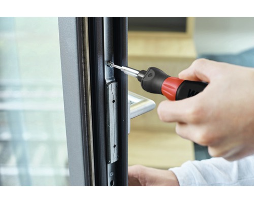 Artisan fixe une vis dans le cadre de la fenêtre avec un tournevis