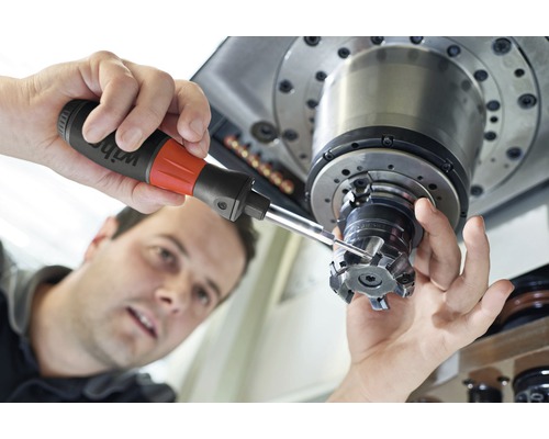 Un homme travaille sur une machine-outil avec un outil de précision.