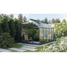Gewächshaus mit Glaswänden und einem Stuhl im Inneren in einem Garten.