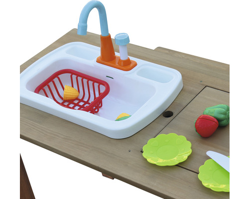 Cuisine jouet avec évier, vaisselle jouet et aliments jouets sur une table en bois.