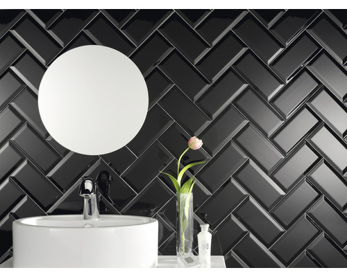 Salle de bain avec carrelage noir brillant à chevrons, miroir rond et lavabo