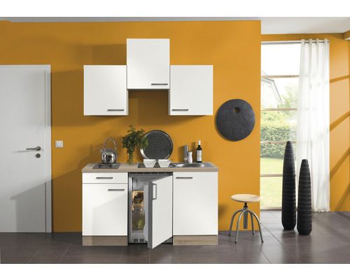 Cuisine compacte avec évier, plaque de cuisson, réfrigérateur et éléments hauts dans une pièce lumineuse