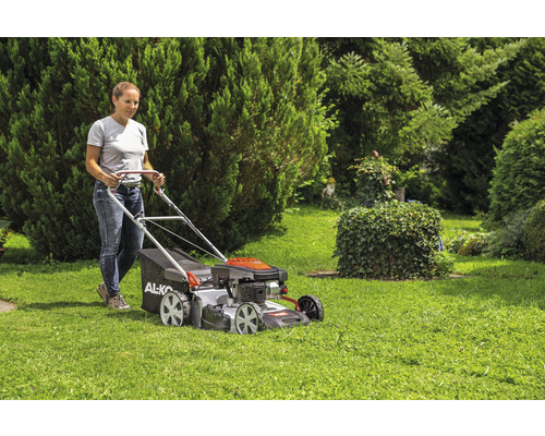 Une femme utilise une tondeuse à gazon dans le jardin.
