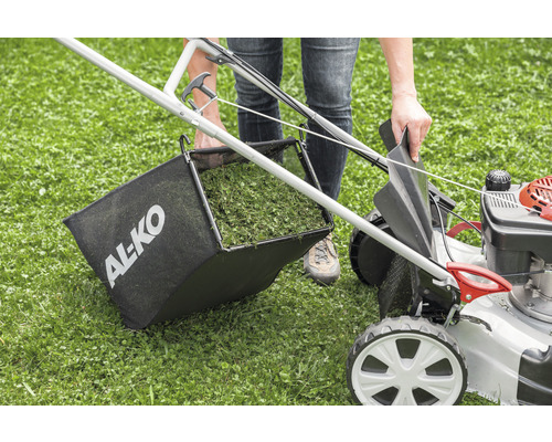 Une personne vide le bac de ramassage d''une tondeuse à essence AL-KO.