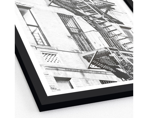 Photographie en noir et blanc d''un bâtiment avec une échelle de secours dans un cadre