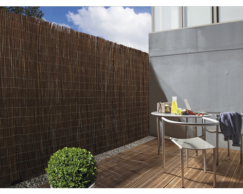 Sichtschutzzaun aus Schilfrohr auf einer Terrasse mit Tisch und Stühlen