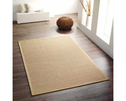 Tapis rectangulaire en fibres naturelles sur plancher en bois dans une pièce lumineuse.