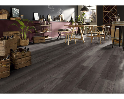 Innenansicht eines Zimmers mit dunkelgrauem Laminatboden, Holztisch mit Stühlen, Regalen und Weinkisten