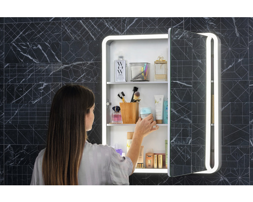 Frau vor einem Spiegelschrank mit Beleuchtung im Badezimmer