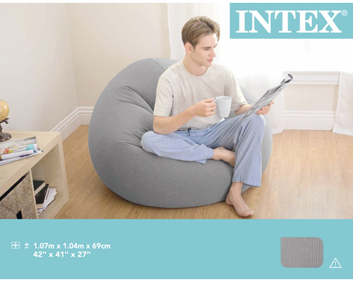 Logo Intex. Un homme est assis avec une tasse et un journal sur un pouf gris.