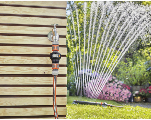 Scène de jardin avec robinet, compteur d''eau Gardena et arroseur de pelouse