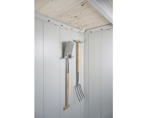 Outils de jardin tels que bêche et fourche sur un support mural dans une cabane de jardin