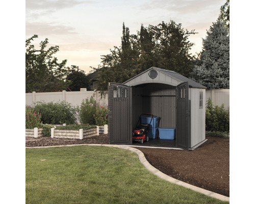 Abri de jardin avec portes ouvertes, tondeuse à gazon et boîtes de rangement à l''intérieur.