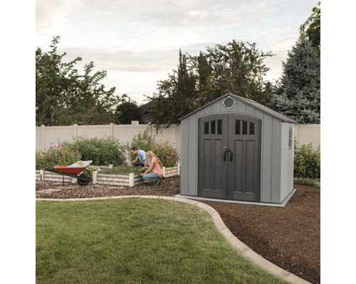 Scène de jardin avec abri de jardin et deux personnes jardinières