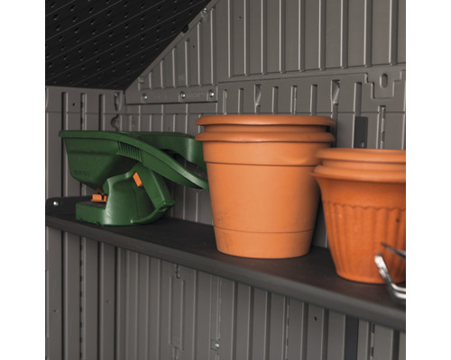 Étagère dans une remise de jardin avec outils de jardin et pots de fleurs.