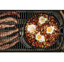 Speck und Eier mit Kartoffeln und Paprika zubereitet in einer Weber Pfanne auf einem Grill.