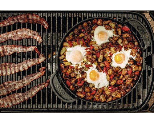 Speck und Eier mit Kartoffeln und Paprika zubereitet in einer Weber Pfanne auf einem Grill.