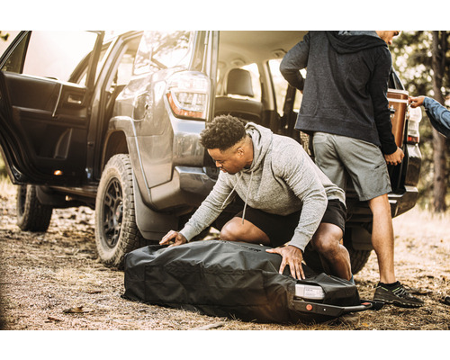 Person packt Tasche am Auto für Outdoor Abenteuer