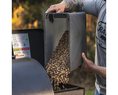 Eine Person füllt Pellets in einen Grill.