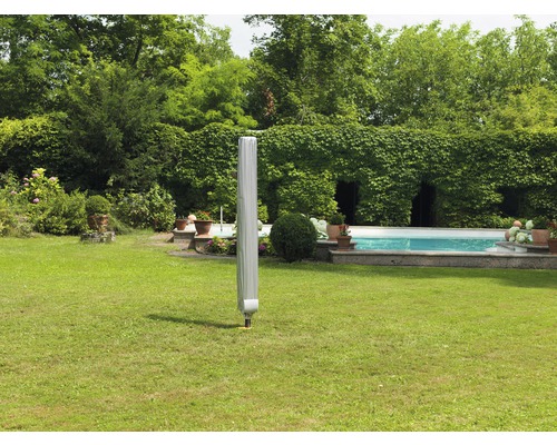 Parasol de jardin fermé avec housse de protection sur une pelouse dans un jardin avec piscine