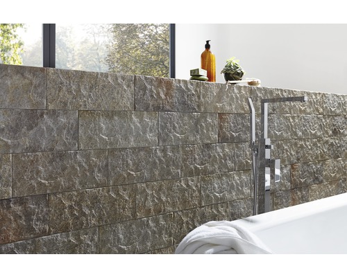 Aménagement de salle de bains avec mur en pierre naturelle, baignoire et robinetterie