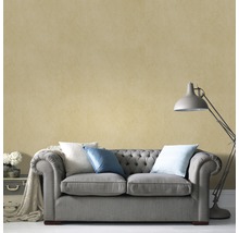 Salon avec canapé gris, coussins et lampadaire devant un mur texturé