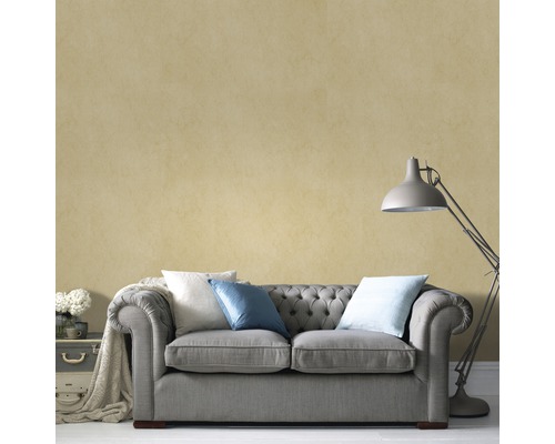 Salon avec canapé gris, coussins et lampadaire devant un mur texturé