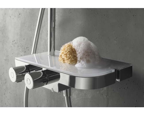 Thermostat de douche avec étagère, éponge de bain et mousse sur fond gris.