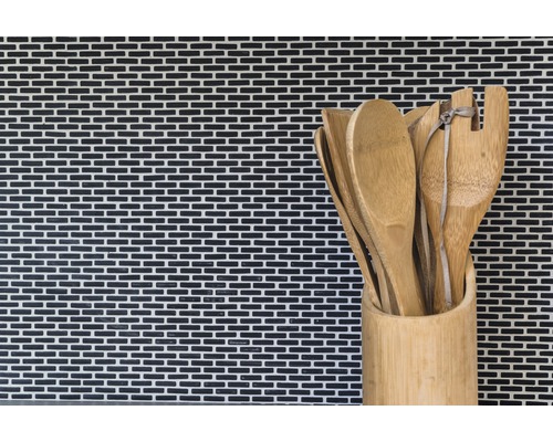 Cuillères en bois et spatules dans un récipient en bambou devant un mur en mosaïque