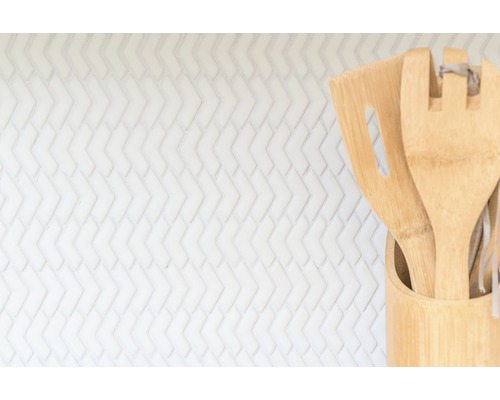 Ustensiles de cuisine en bambou dans un récipient devant un fond blanc