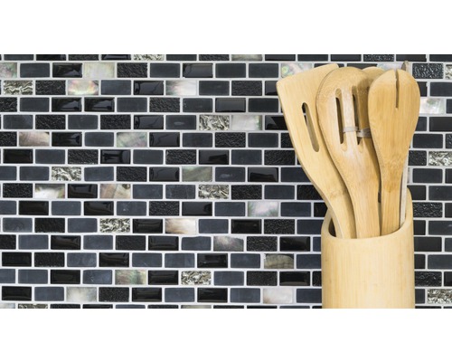 Küchenutensilien aus Holz in einem Behälter vor einer Mosaikwand