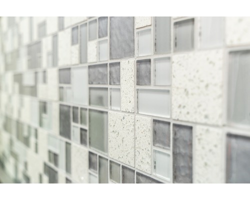 Gros plan d''un mur avec des carreaux de mosaïque dans différentes nuances de gris et textures.