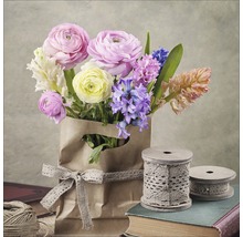 Blumenstrauß mit Ranunkeln und Hyazinthen in einer Papiertüte mit Spitze, umgeben von Garnrollen und Büchern