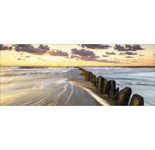 Sonnenuntergang am Strand mit Holzpfosten im Wasser