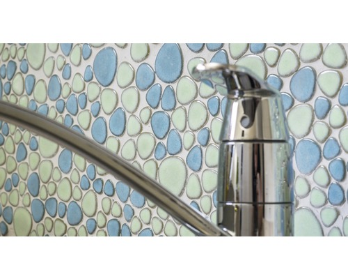 Gros plan d''un robinet devant un mur avec des carreaux de mosaïque à motif de galets