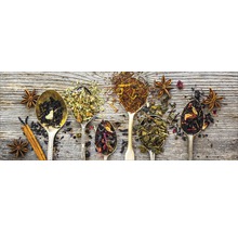 Verschiedene Teesorten in Löffeln mit Sternanis und Zimtstange auf Holzgrund.