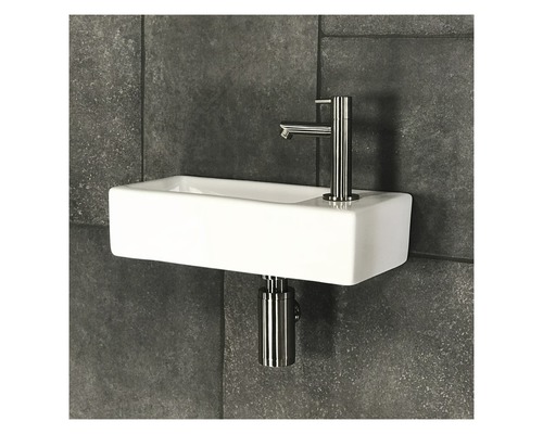 Keramik Waschbecken mit Armatur und Siphon vor dunklem Fliesenhintergrund