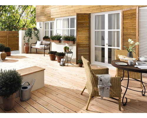 Terrasse en bois clair avec mobilier de jardin, plantes et éléments décoratifs devant une maison avec façade en bois