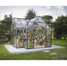 Gewächshaus mit Glaswänden, ausgestattet mit Möbeln und Pflanzen, im Garten.