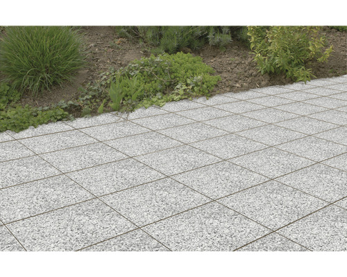 Dalles de terrasse carrées en pierre à l''extérieur, à côté d''une zone de plantation