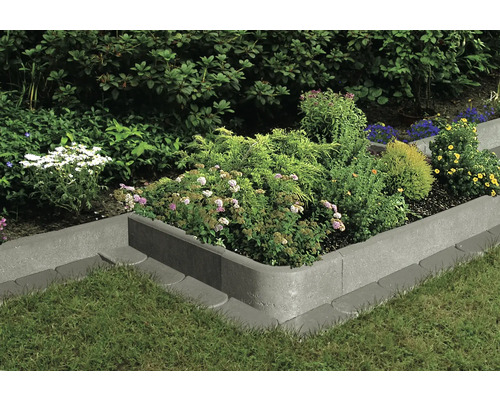 Bordure de parterre en béton avec plantations dans le jardin.