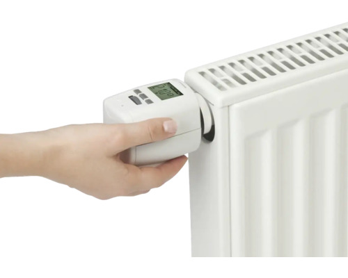 La main installe un thermostat de radiateur électronique sur un radiateur