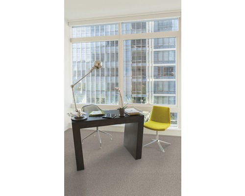 Büroraum mit Schreibtisch, Bürostuhl, Lampe und Fenster mit Blick auf ein Gebäude