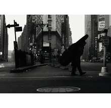 Schwarzweißfoto einer Stadtstraße mit einer Person, die einen Kontrabass trägt