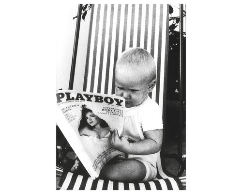 Ein Kind sitzt auf einem gestreiften Stuhl und liest ein Playboy-Magazin.