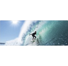 Un surfeur surfe sur une vague sous un ciel clair.