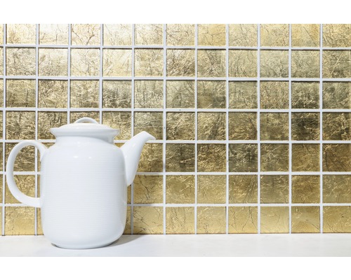 Mosaïque dorée en arrière-plan avec une théière blanche au premier plan