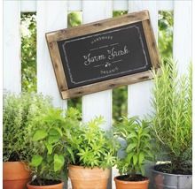 Holzschild mit der Aufschrift ''Farm Fresh'' hängt an einem Gartenzaun neben Kräutertöpfen.