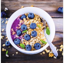Müslischale mit Heidelbeeren und Löffel auf einem Holztisch