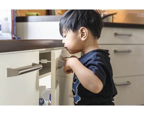 Kind versucht eine Schublade mit Kindersicherung zu öffnen